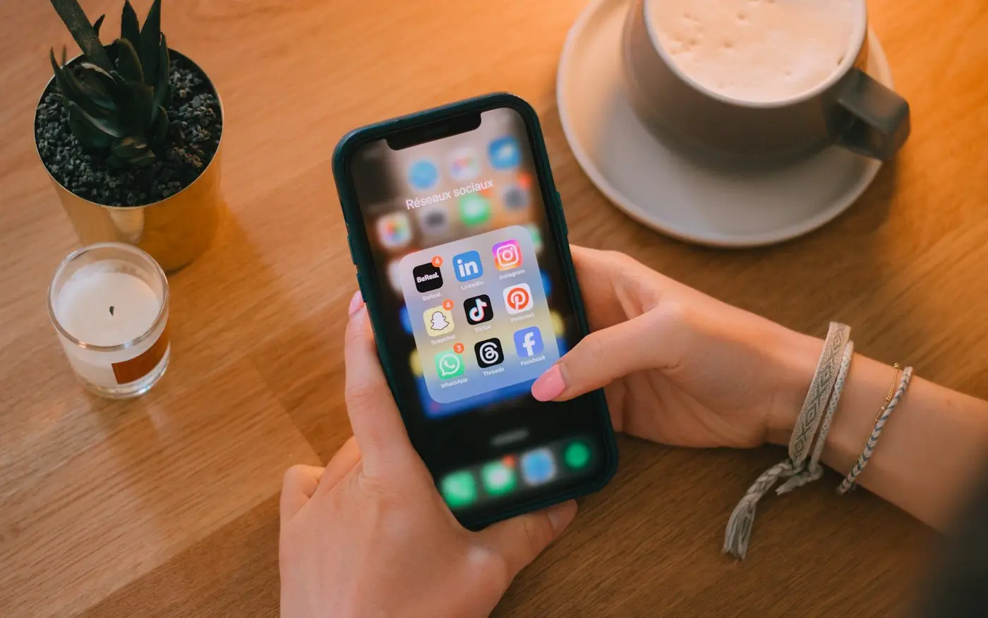 Phone showing social media apps on a wooden table